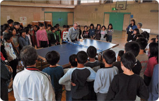 卓球台の周りに大勢の小学生たちが取り囲んでいる